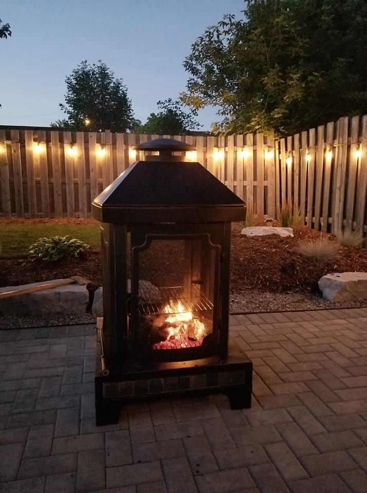 Metal fire pit with a small fire inside on an outdoor patio