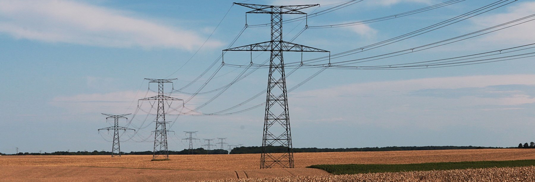 hydro towers in a field against a blue sky